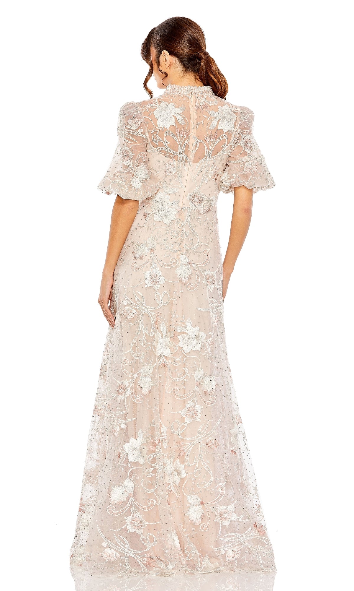 A woman with brown hair in a ponytail is seen from the back wearing the Mac Duggal 20452—a floor-length sheer formal dress with short flutter sleeves and delicate floral embroidery.
